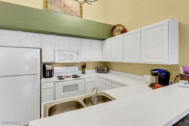 Kitchen featuring white appliances, white cabinetry, and light countertops | Image 11