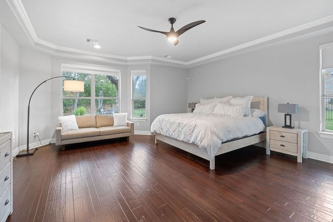 Bedroom with baseboards, wood-type flooring, a raised ceiling, and crown molding | Image 14