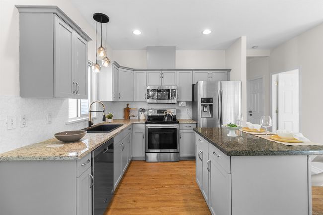 Kitchen with appliances with stainless steel finishes, a sink, gray cabinets, light wood-type flooring, and recessed lighting | Image 15