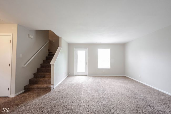 unfurnished living room featuring carpet floors, stairs, and baseboards | Image 6