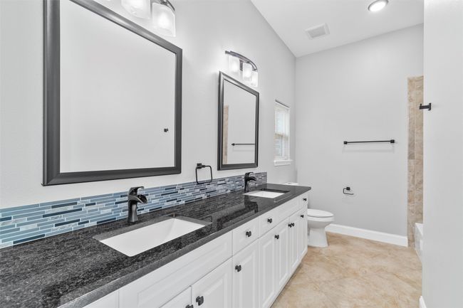 Full bathroom with tile flooring, double sink vanity, shower combination, tasteful backsplash, and toilet | Image 20