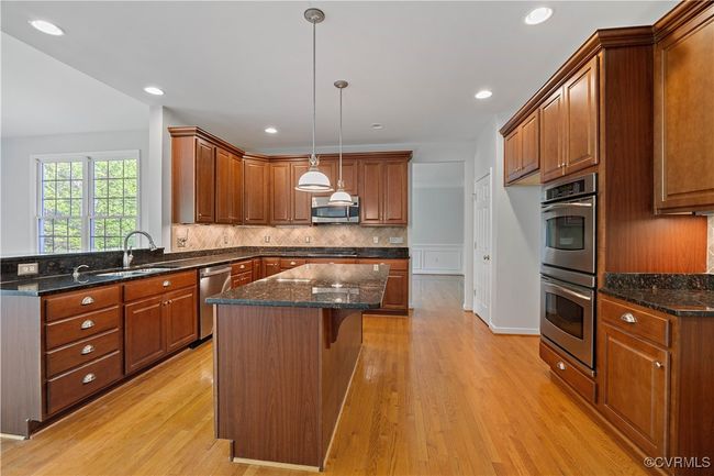 Kitchen featuring tasteful backsplash, light wood-style floors, appliances with stainless steel finishes, a kitchen island, and a sink | Image 15