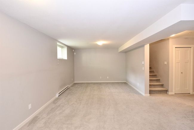 Below grade area with a baseboard radiator, light carpet, and stairway | Image 33