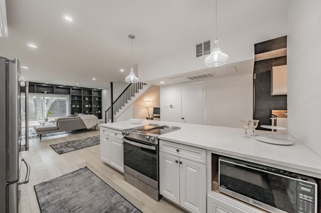 Kitchen with white cabinets, open floor plan, visible vents, and appliances with stainless steel finishes | Image 7