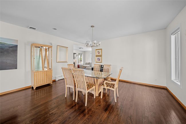 Dining space with a chandelier, visible vents, a baseboard heating unit, and dark wood-type flooring | Image 4