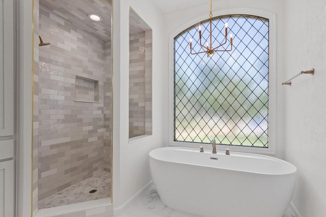 Bathroom featuring baseboards, a chandelier, a soaking tub, marble finish flooring, and tiled shower | Image 23