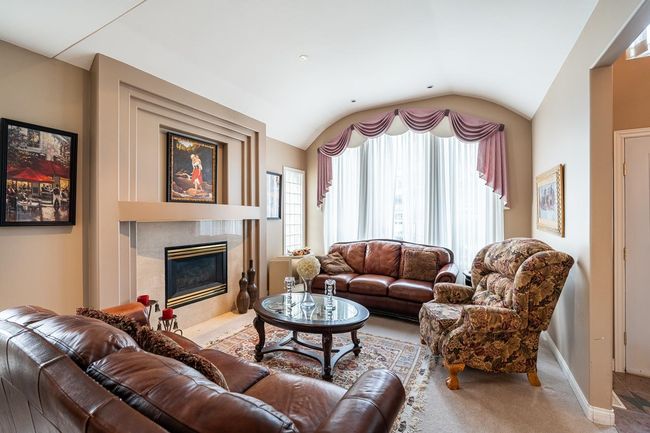 Carpeted living room featuring a tiled fireplace, baseboards, and lofted ceiling | Image 9