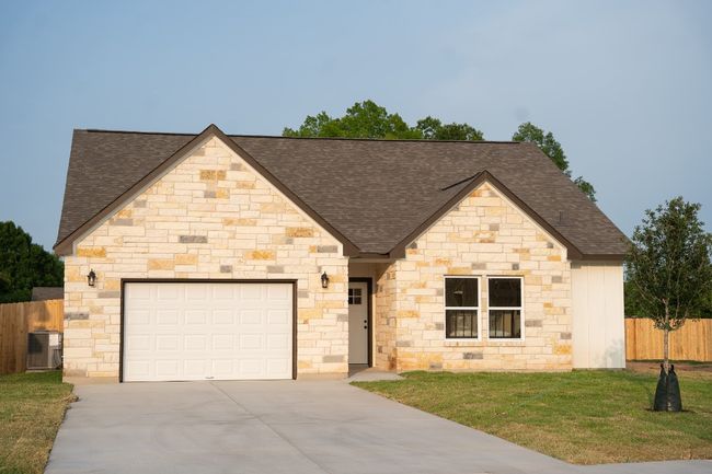 French country style house with a shingled roof, concrete driveway, an attached garage, cooling unit, and stone siding | Image 6