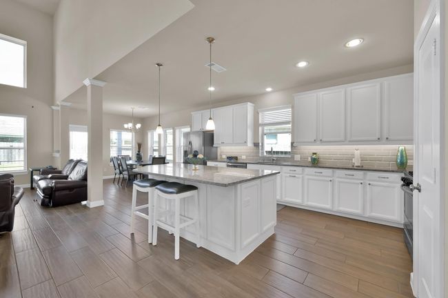If you head down the hall you'll meet your elegant future kitchen. This entertainer's kitchen is complete with white cabinetry, pendant and recessed lighting, a stylish and modern backsplash, and a large island to set this kitchen apart from the competition. | Image 7