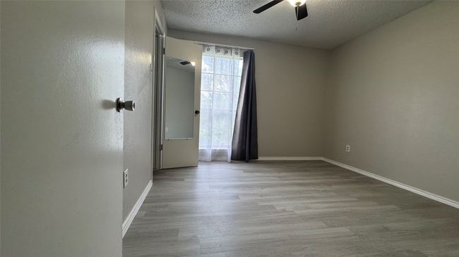 Unfurnished room with a textured ceiling, a ceiling fan, baseboards, and wood finished floors | Image 16