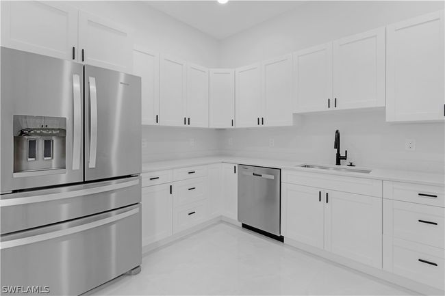 Kitchen with stainless steel appliances, sink, light tile flooring, and white cabinets | Image 34