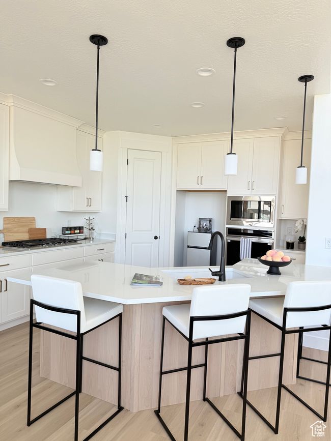Kitchen with appliances with stainless steel finishes, light wood-type flooring, light countertops, white cabinetry, and recessed lighting | Image 5