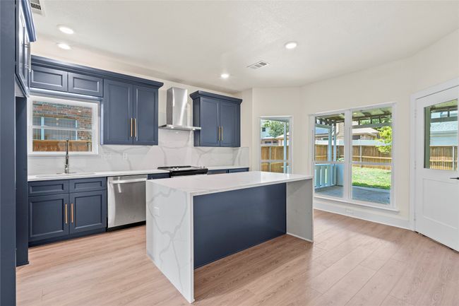 Kitchen with wall chimney exhaust hood, dishwasher, light wood-type flooring, recessed lighting, and backsplash | Image 8