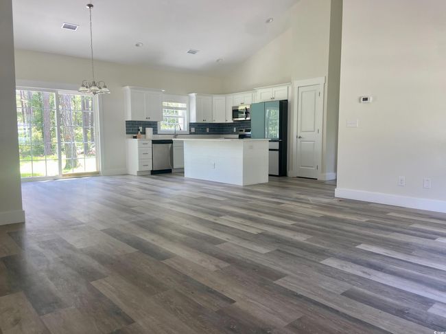 Kitchen with appliances with stainless steel finishes, open floor plan, white cabinetry, a kitchen island, and wood finished floors | Image 9