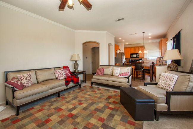 Living room with arched walkways, crown molding, a ceiling fan, carpet floors, and recessed lighting | Image 9