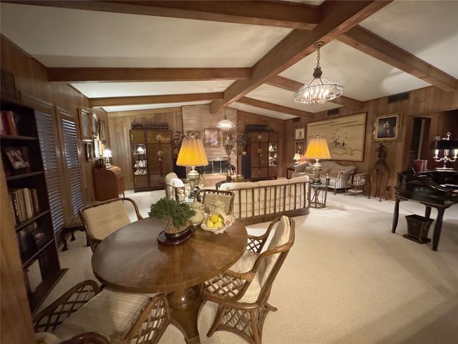 Dining room featuring wooden walls, a chandelier, and carpet flooring | Image 16