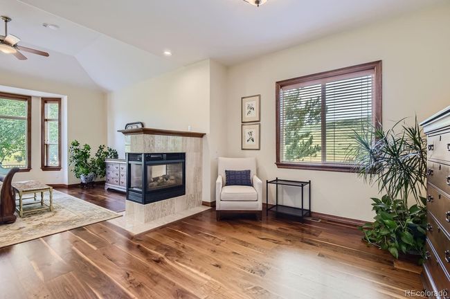 3-sided fireplace and sitting area in main floor primary suite! | Image 28