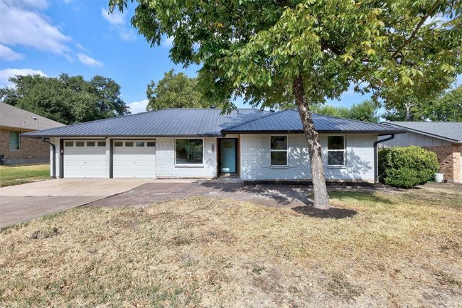 Ranch-style home with an attached garage, brick siding, concrete driveway, a metal roof, and a front yard | Image 4