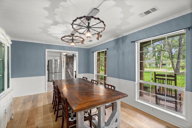This dining room is brightened by large windows offering views of the lush greenery in the front yard. | Image 6