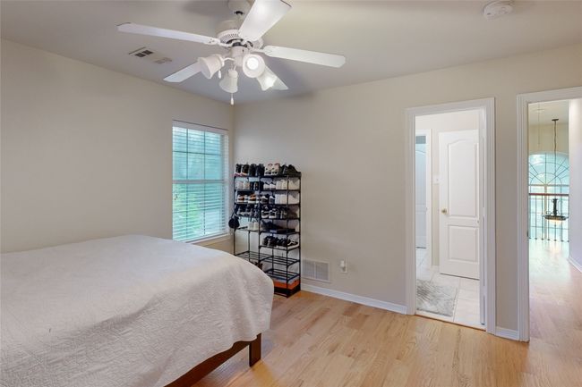 Bedroom with light wood finished floors, baseboards, visible vents, and ceiling fan | Image 22