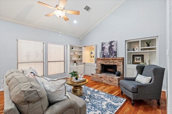 Living area with light wood-style flooring, high vaulted ceiling, built in features, ornamental molding, and a ceiling fan | Image 6