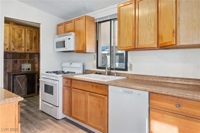 Kitchen featuring light wood-style flooring, white appliances, a sink, vaulted ceiling, and light countertops | Image 10