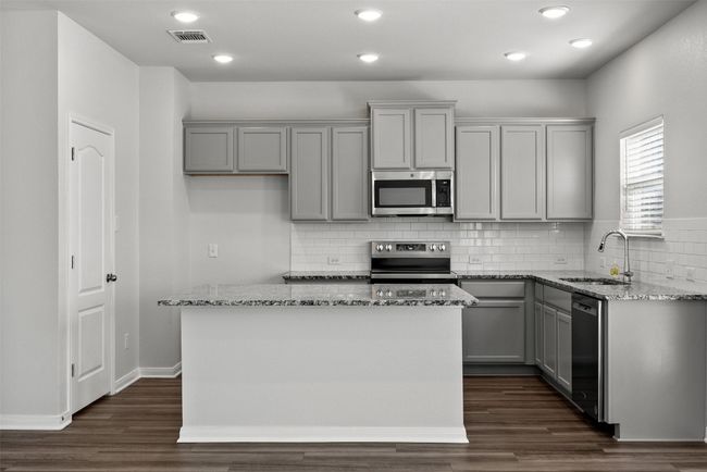 Kitchen with stainless steel appliances, gray cabinets, light stone countertops, wood-look tile floors, and recessed lighting | Image 10