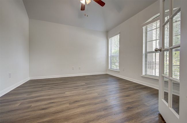Empty room with a ceiling fan, dark wood-style flooring, and lofted ceiling | Image 6