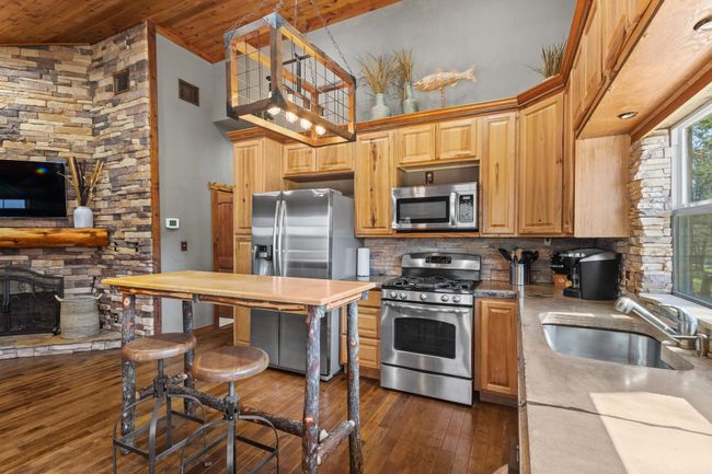 Kitchen with decorative backsplash, visible vents, appliances with stainless steel finishes, a sink, and dark wood-style floors | Image 23