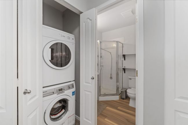 Washroom with laundry area, wood finished floors, visible vents, and stacked washer and dryer | Image 13