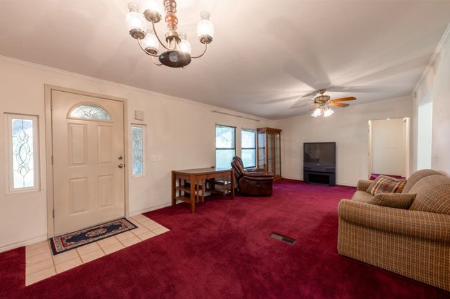 Carpeted entrance foyer with a chandelier, ornamental molding, tile patterned flooring, and ceiling fan | Image 15