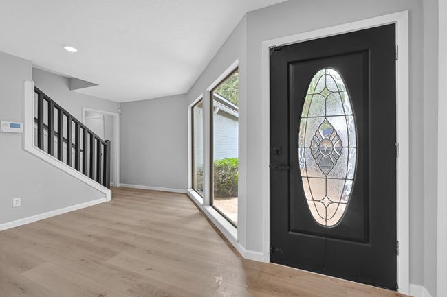 Welcoming front entry with large picture windows and a decorative glass front door. Natural light fills the space and highlights the brand-new flooring and freshly painted walls and trim. | Image 6