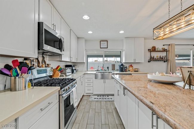 Kitchen featuring wood finish floors, recessed lighting, a sink, stainless steel appliances, and white cabinets | Image 10
