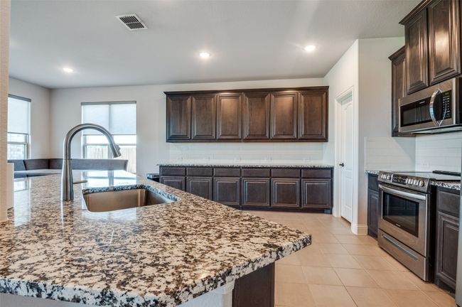 Kitchen with stainless steel appliances, dark brown cabinetry, backsplash, and recessed lighting | Image 10