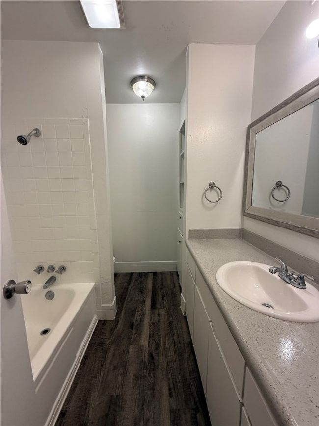 Full bathroom featuring vanity, wood finished floors, and washtub / shower combination | Image 8