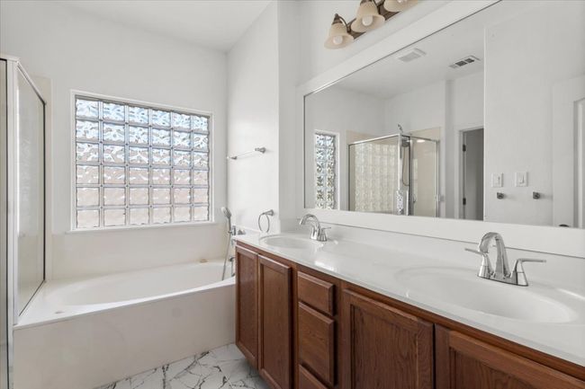 Full bathroom featuring a bath, a shower stall, double vanity, and marble look tile flooring | Image 29