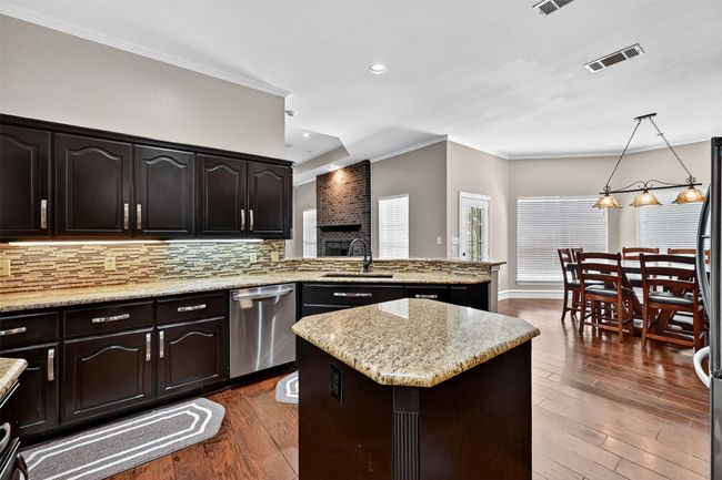 Kitchen with dishwasher, a sink, dark wood-style flooring, a center island, and backsplash | Image 13