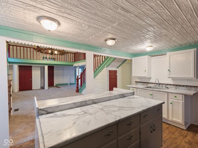 kitchen with white cabinetry, wood finished floors, wooden ceiling, and a sink | Image 13
