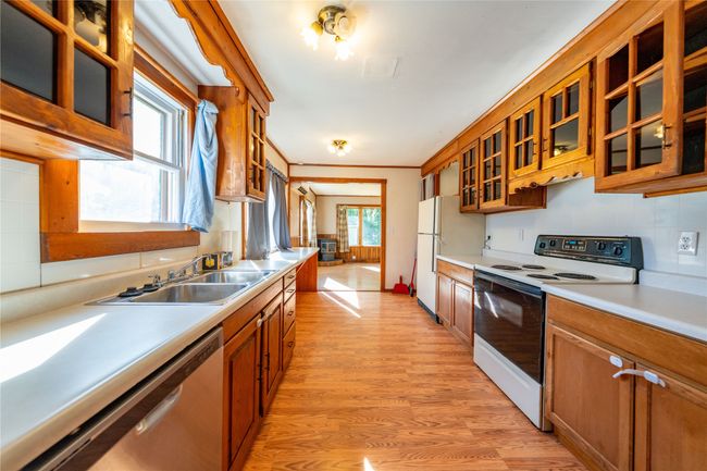 Kitchen featuring range with electric cooktop, stainless steel dishwasher, and brown cabinetry | Image 11