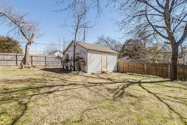 Fenced backyard featuring a storage unit | Image 17