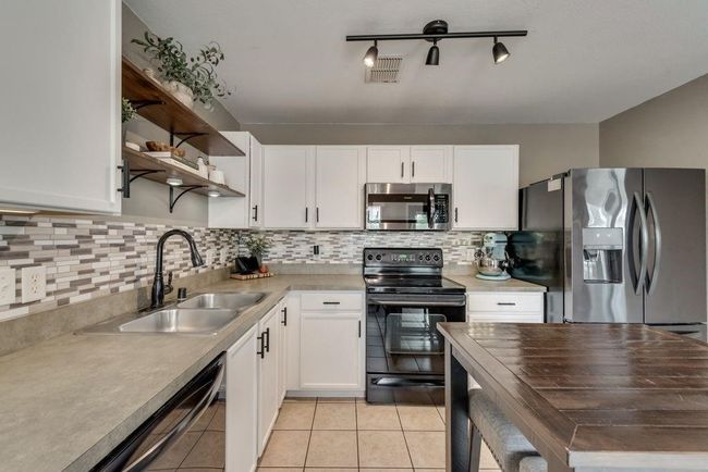 Kitchen featuring black appliances, white cabinetry, open shelves, and light countertops | Image 13