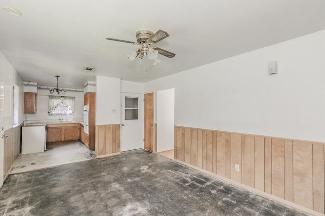 Unfurnished living room featuring wood walls, a ceiling fan, a wainscoted wall, and concrete flooring | Image 18