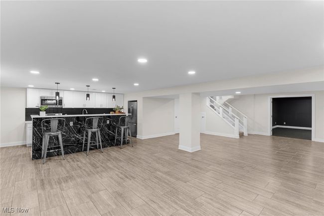 Kitchen with appliances with stainless steel finishes, open floor plan, recessed lighting, a kitchen bar, and white cabinetry | Image 37