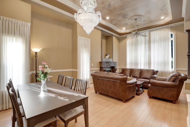 Living room featuring light wood-type flooring, a raised ceiling, crown molding, and plenty of natural light | Image 4