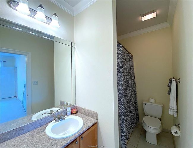 Full bathroom with crown molding, vanity, toilet, tile patterned flooring, and curtained shower | Image 6