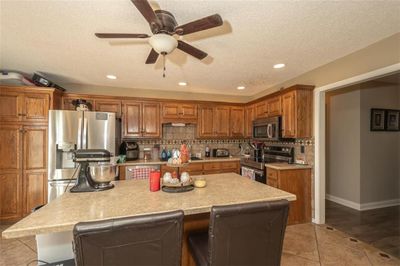 Kitchen with stainless steel appliances, a textured ceiling, a kitchen bar, and a kitchen island | Image 3