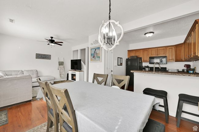 Dining area with dark wood-type flooring, ceiling fan with notable chandelier, and visible vents | Image 24