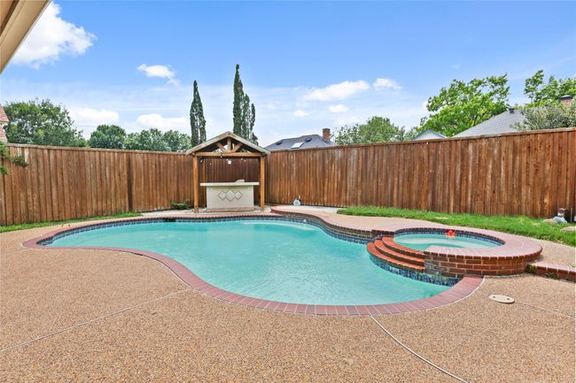 View of pool with a fenced backyard, a pool with connected hot tub, and a patio area | Image 31