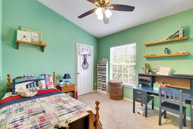 Bedroom with vaulted ceiling, carpet, baseboards, a ceiling fan, and an office area | Image 28