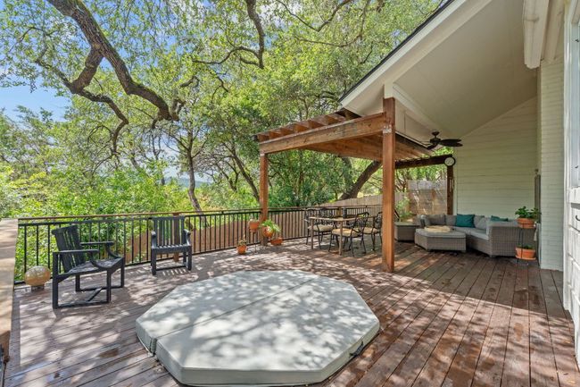 Wooden terrace featuring an outdoor hangout area, outdoor dining area, ceiling fan, and view of wooded area | Image 33